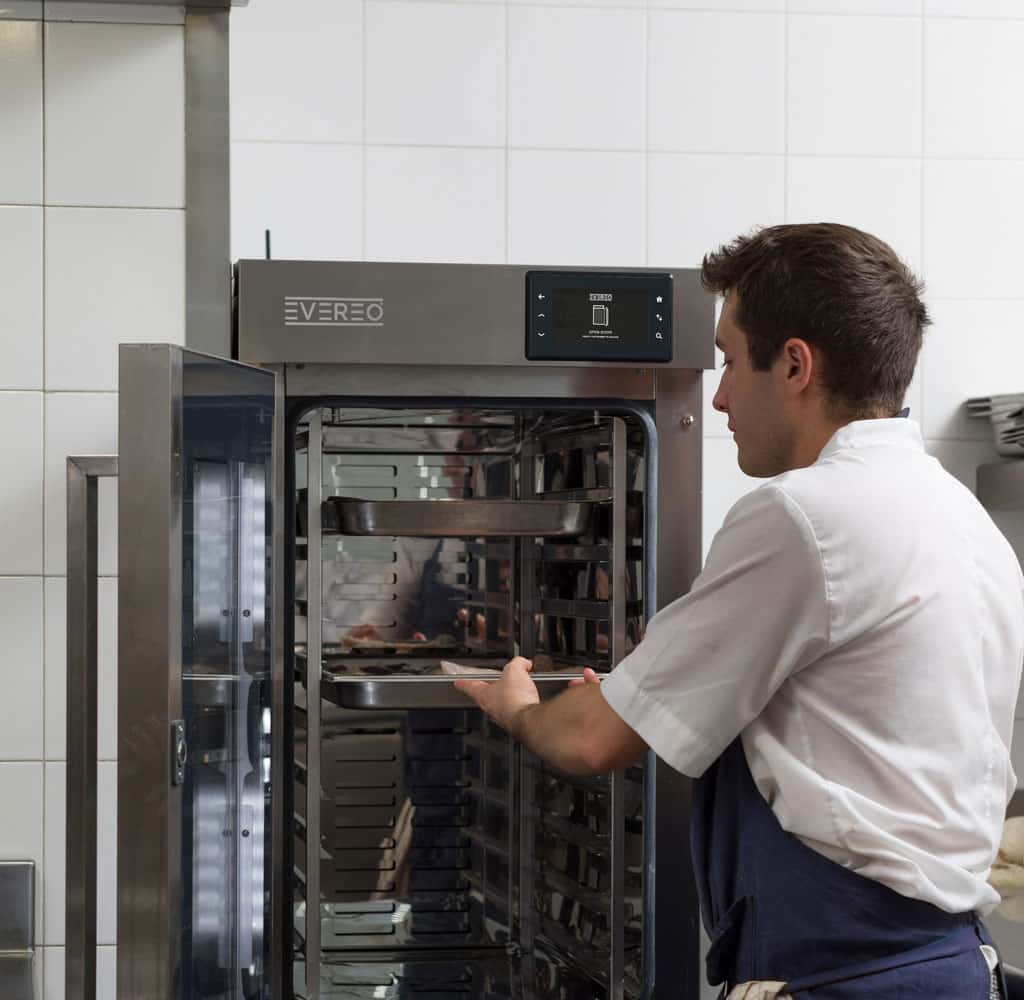 Male kitchen professional loading a tray with ready-to-serve food into the unox evereo hot fridge.