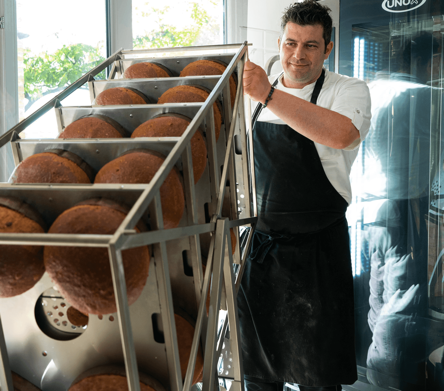 Chef inversant une charge complète de panettoni sur un chariot pour four professionnel mixte Unox