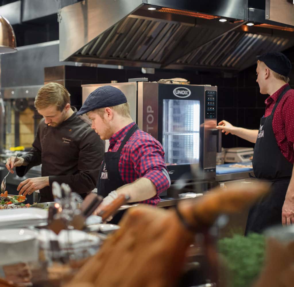 male chef opening the door of a Unox commercial combi oven inside a restaurant kitchen