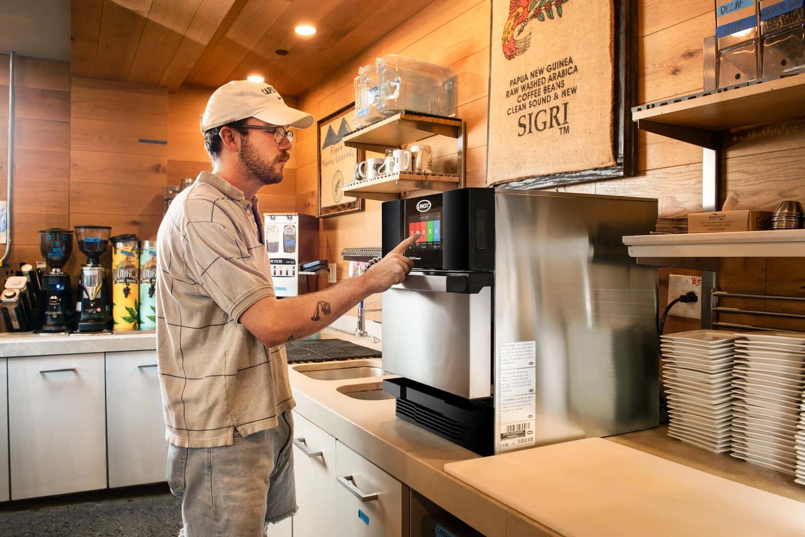 Un uomo che lavora in un locale della ristorazione rapida utilizza un forno veloce professionale Unox, interagendo senza sforzo con il suo pannello touchscreen.