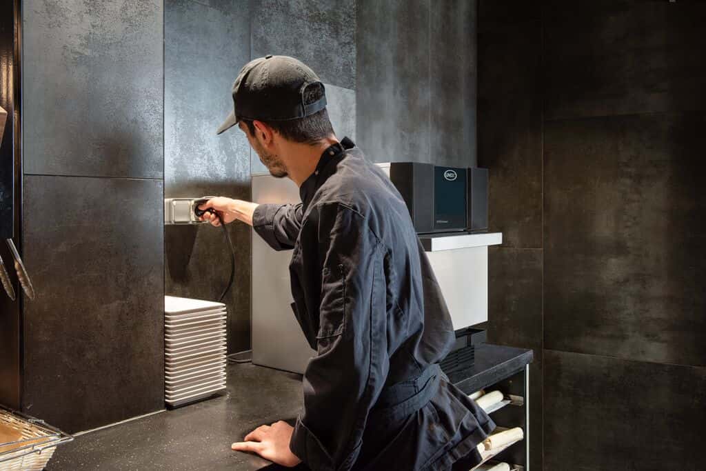 Un dipendente della caffetteria in maglietta nera collega facilmente un forno rapido professionale Unox sul bancone.